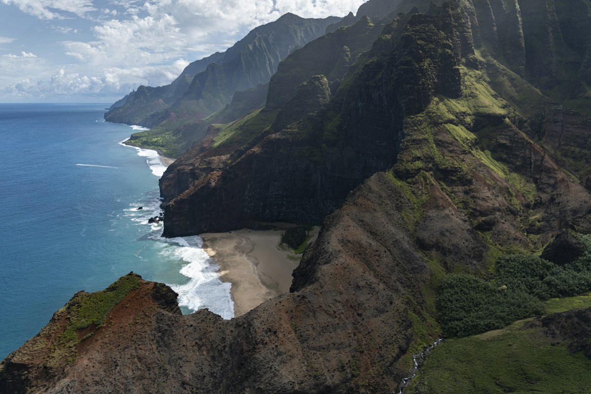 Green cliffs of the Nā Pali coast meeting the Pacific Ocean in Hawaii
